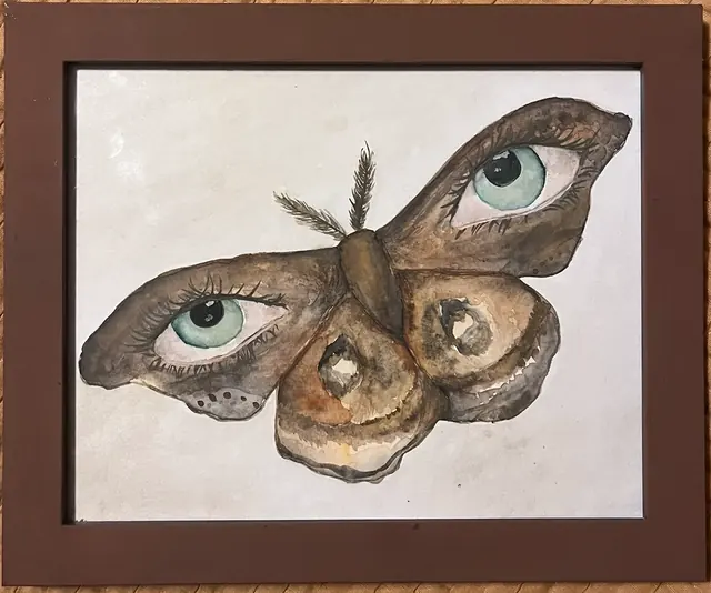 Framed watercolor of a brown moth whose wings carry two realistic blue-green eyes